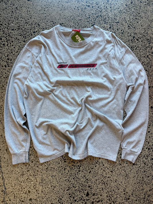 Early 2000s Reebok long sleeve T-shirt size L laid on polished concrete background — black with bold Reebok logo.