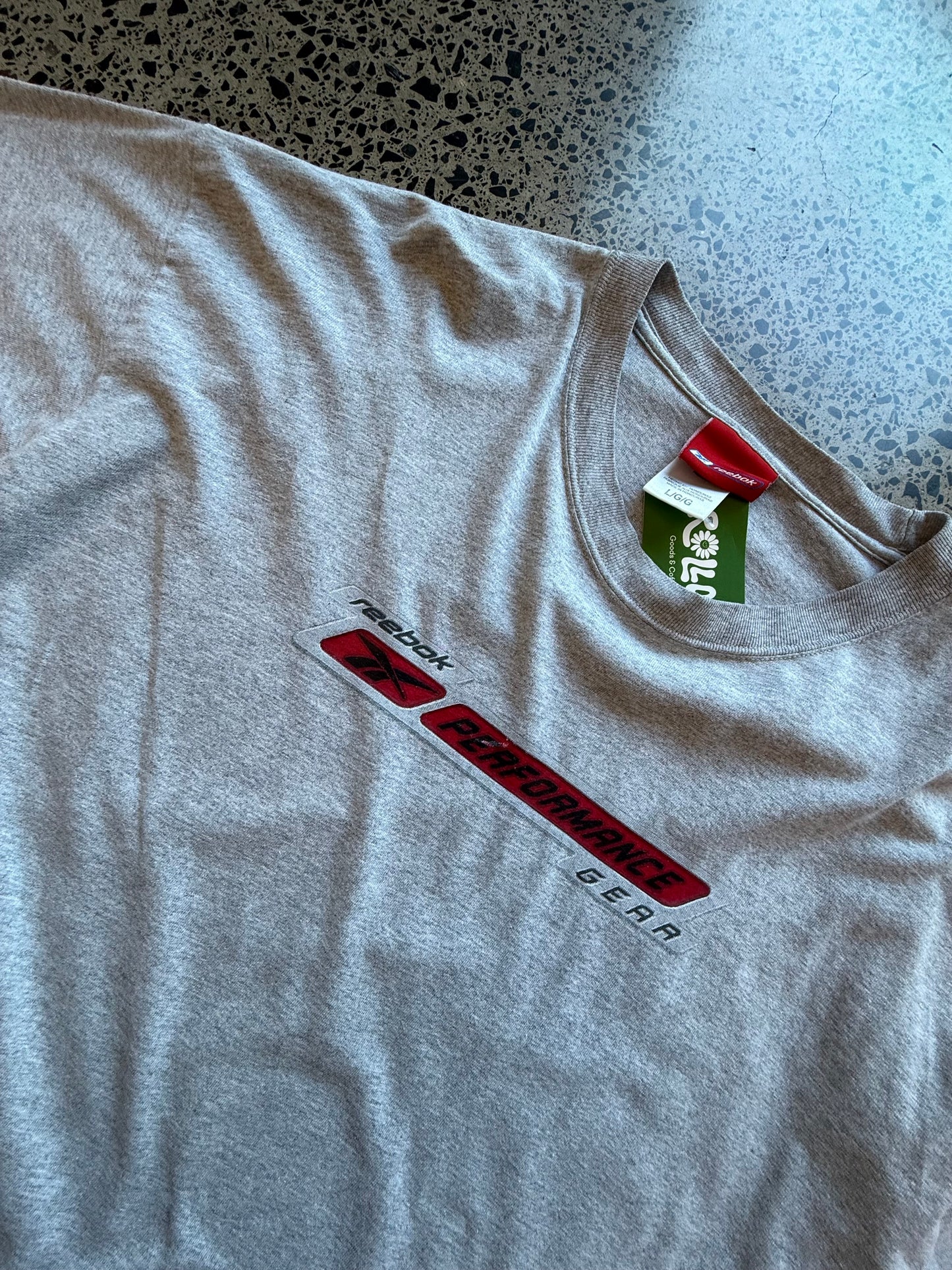 Early 2000s Reebok long sleeve T-shirt size L laid on polished concrete background — black with bold Reebok logo.