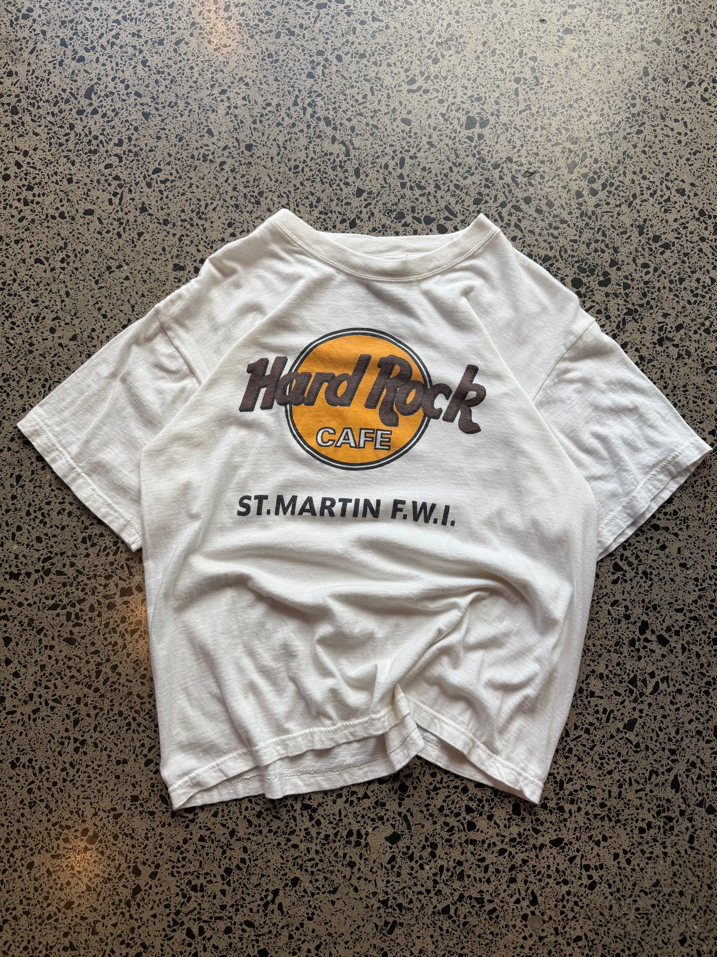 Hard Rock St. Martin graphic T-shirt, size L, laid on polished concrete background — classic Hard Rock logo on soft cotton.
