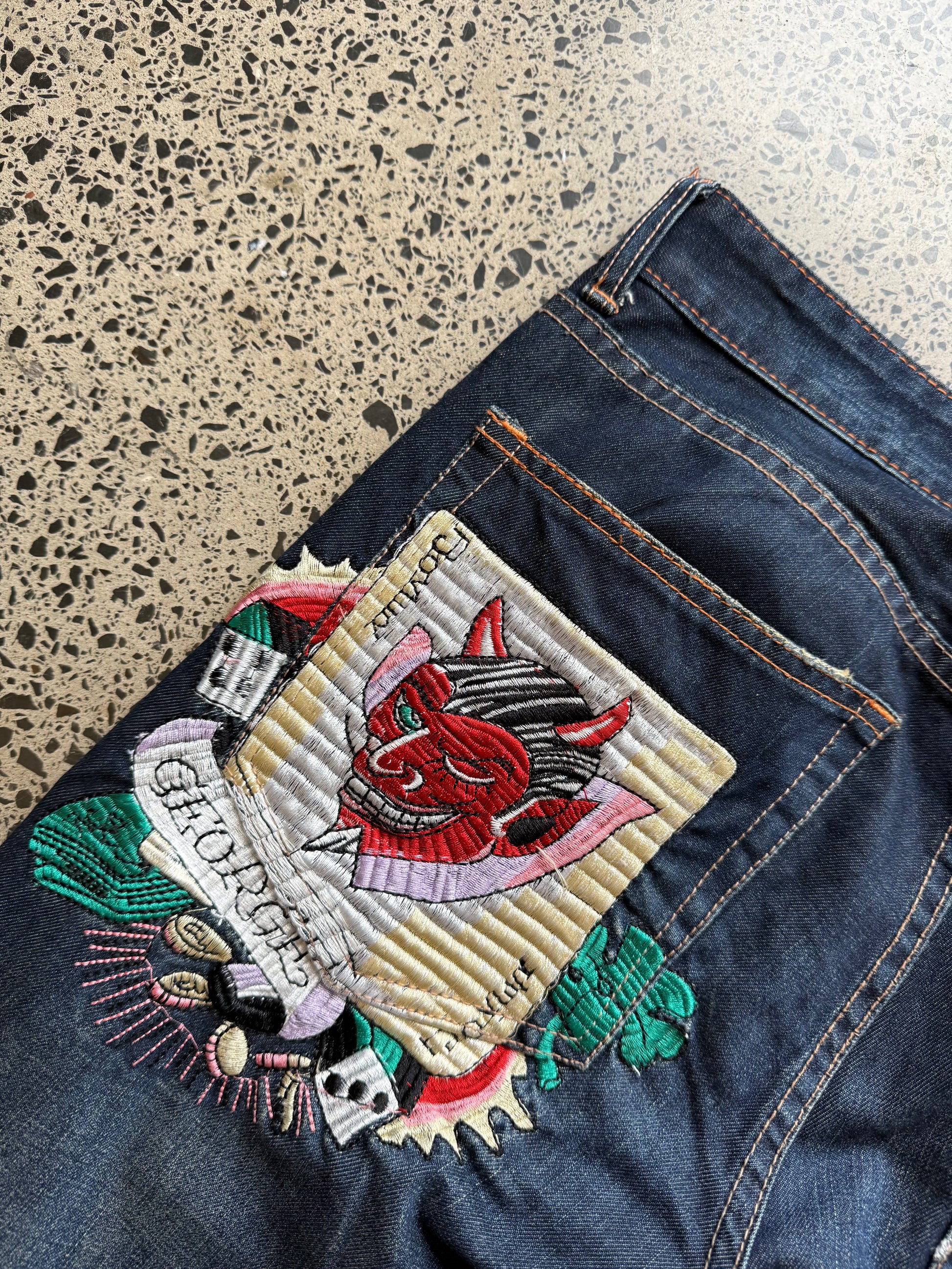Y2K Ed Hardy embroidered dark blue jeans with devil joker playing card graphics. Size W32 L33.