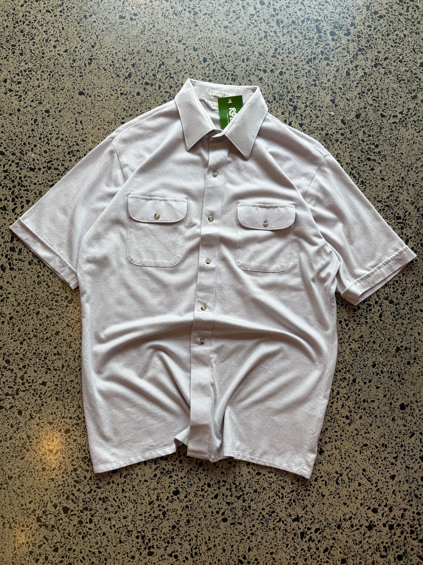 Late 80s early 90s Dior button-up shirt in size L laid flat on a polished concrete background featuring classic vintage designer tailoring.