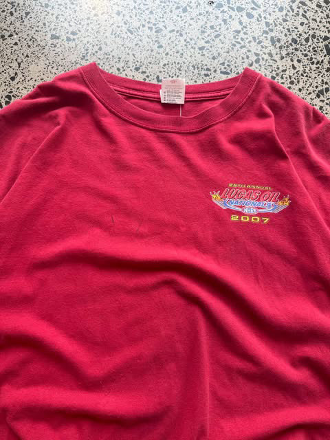2007 Lucas Oil graphic T-shirt laid on a polished concrete background featuring bold motorsport logo artwork.
