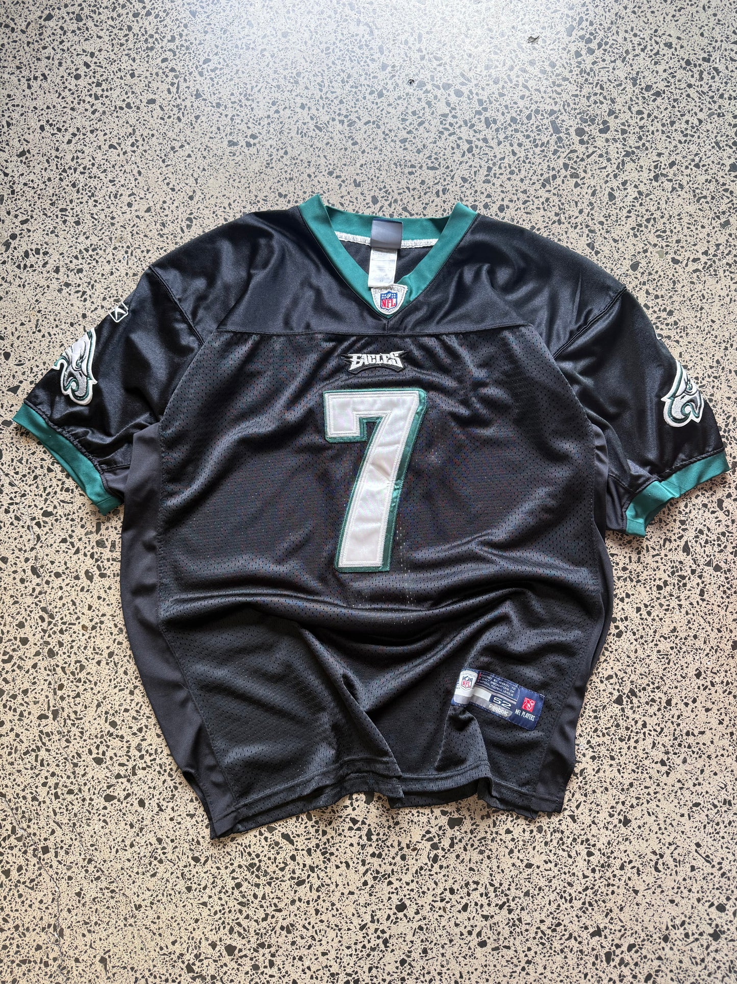 Philadelphia Eagles Michael Vick NFL jersey size 2XL laid on polished concrete background — midnight green with white detailing and Eagles logo.
