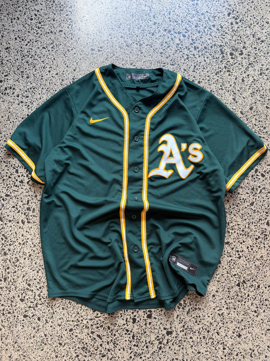 Nike Oakland Athletics MLB jersey size L laid on polished concrete background — green with yellow detailing and Nike logo.