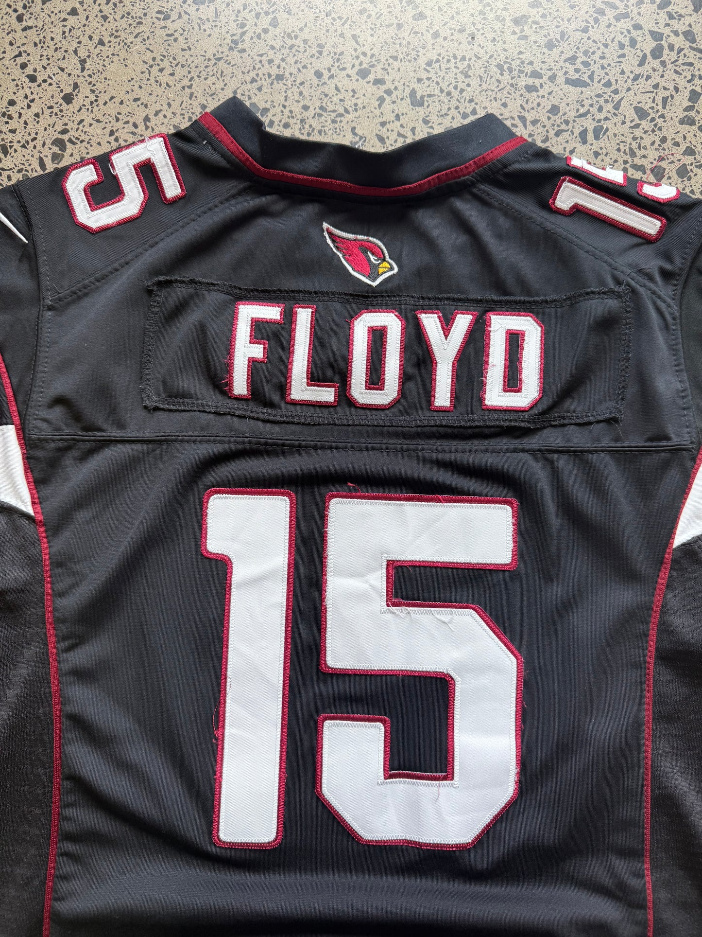 Arizona Cardinals Michael Floyd NFL jersey size L laid on polished concrete background — red with white detailing and Cardinals logo.