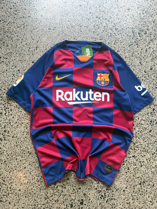 2019/20 FC Barcelona home football jersey size L laid on a polished concrete background featuring the blue and red checkered Barça design.