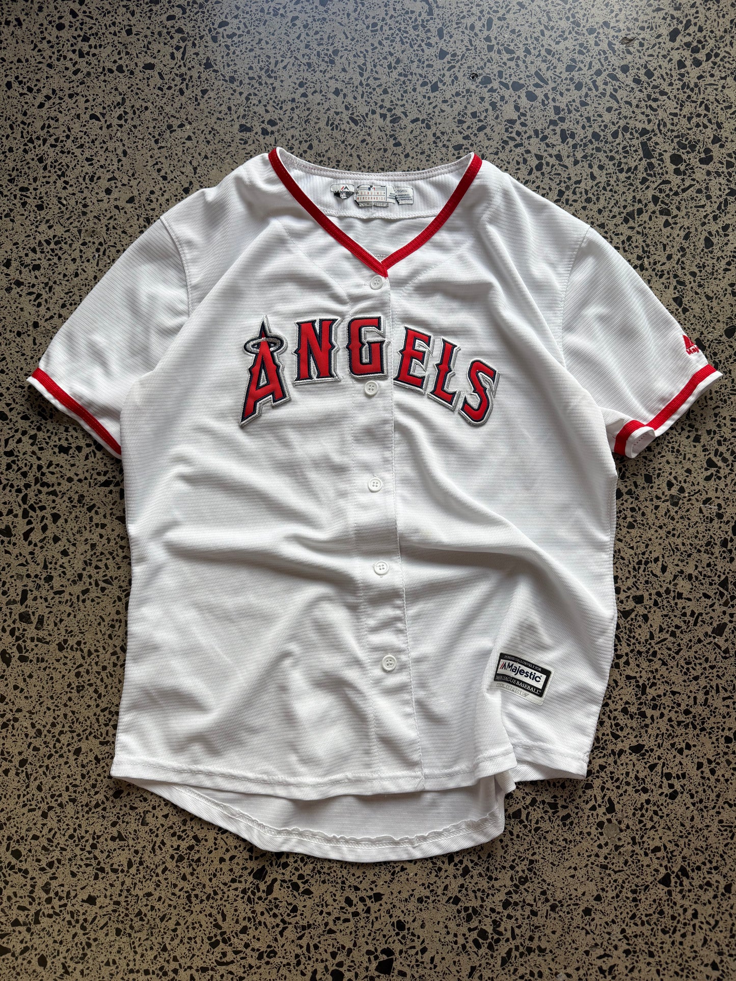 LA Angels Shohei Ohtani MLB baseball jersey size XL laid on polished concrete background — red with white detailing and Angels logo.