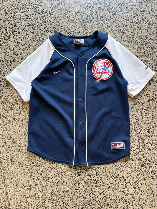 New York Yankees MLB baseball jersey size M laid on polished concrete background — classic navy and white club colours with bold lettering.