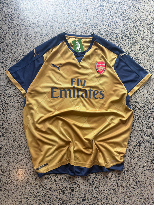 2015/16 Arsenal navy and gold third football jersey in size 2XL laid on a polished concrete background.