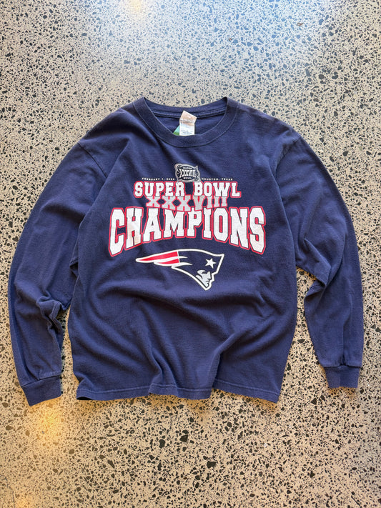 2004 New England Patriots Super Bowl Champions long sleeve shirt M laid flat on polished concrete background, vintage NFL tee with championship graphics and team branding.