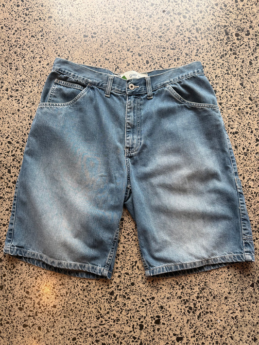 Gap mid-wash blue wash denim jorts, size 34W, laid on polished concrete background. Knee cut with classic stitching and soft wash