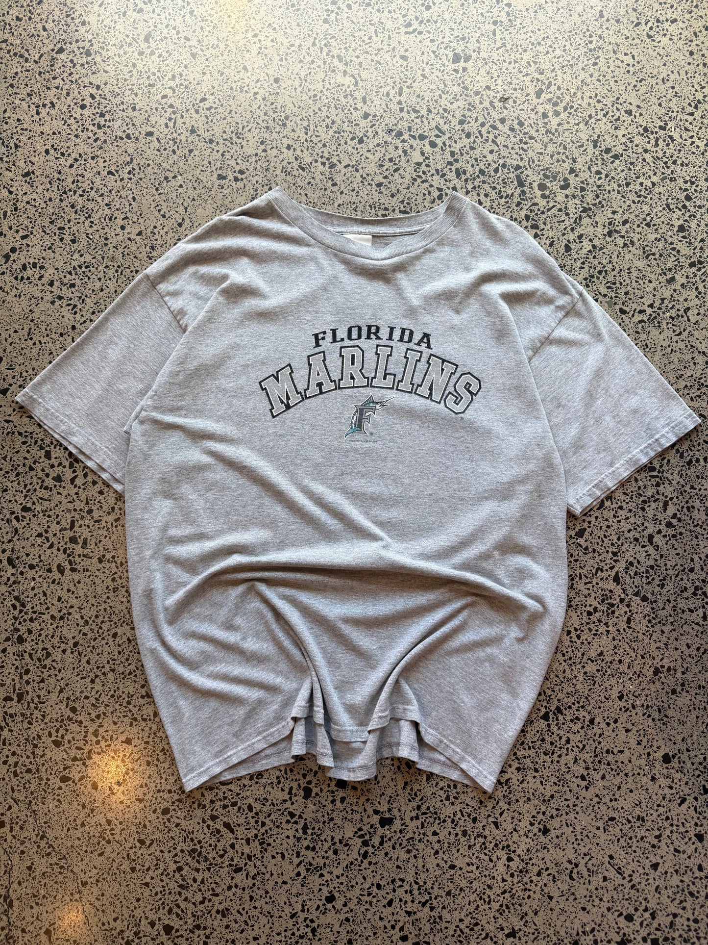 2004 Florida Marlins baseball T-shirt, size 2XL, laid on polished concrete background with early-2000s MLB graphic.