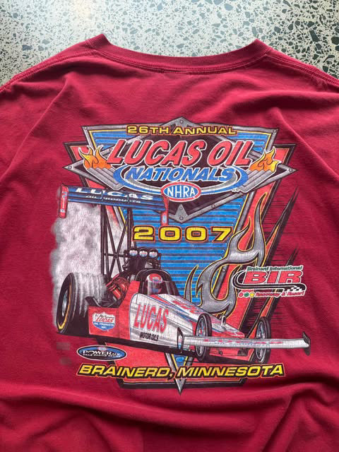 2007 Lucas Oil graphic T-shirt laid on a polished concrete background featuring bold motorsport logo artwork.