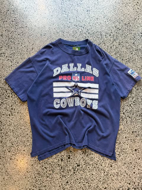 1993 Dallas Cowboys NFL T-shirt in size XL laid on a polished concrete background — vintage early-90s football graphic on soft cotton.