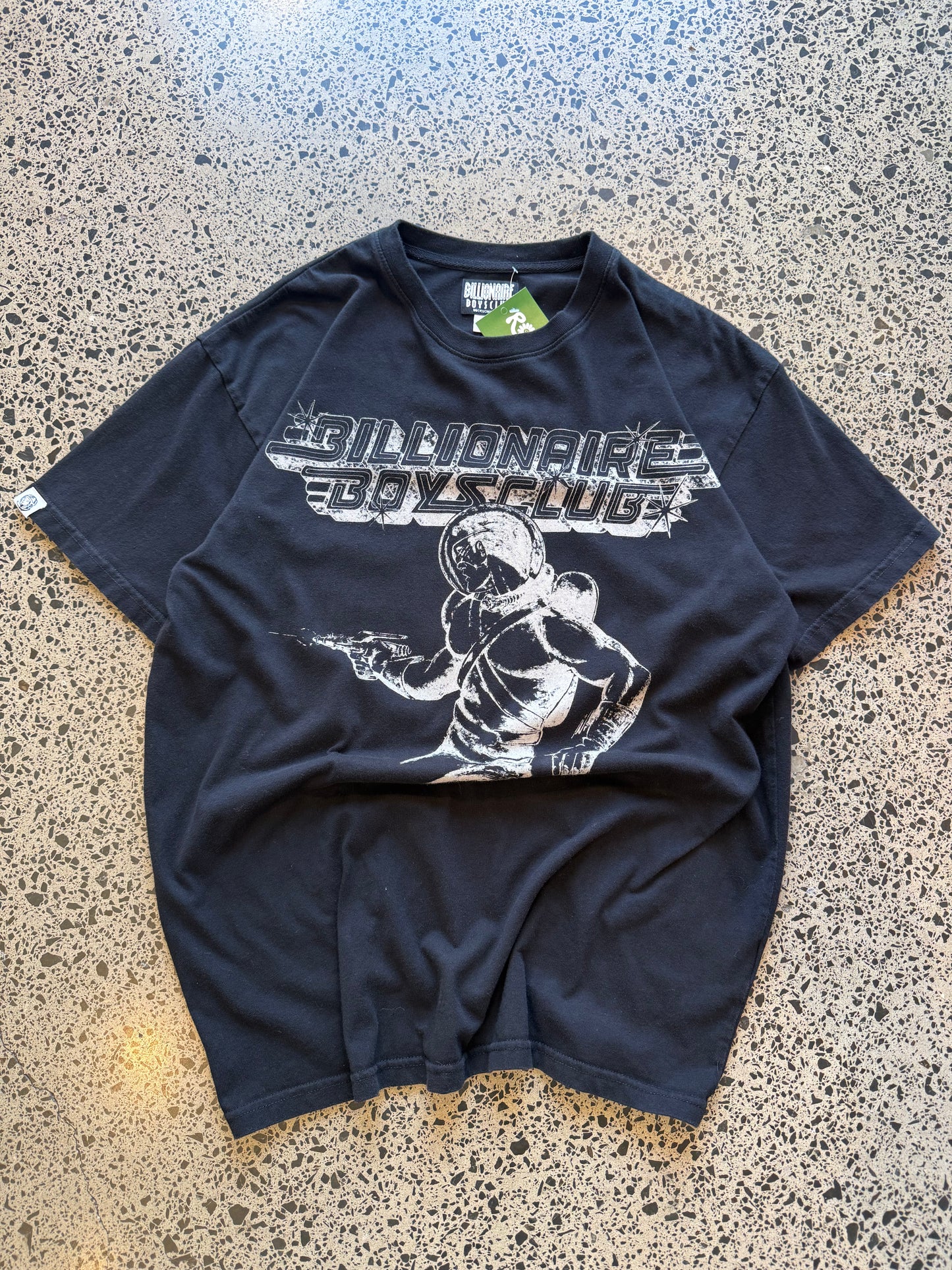 Billionaire Boys Club astronaut T-shirt in black, size M, laid on a polished concrete background — bold white astronaut graphic on soft cotton.