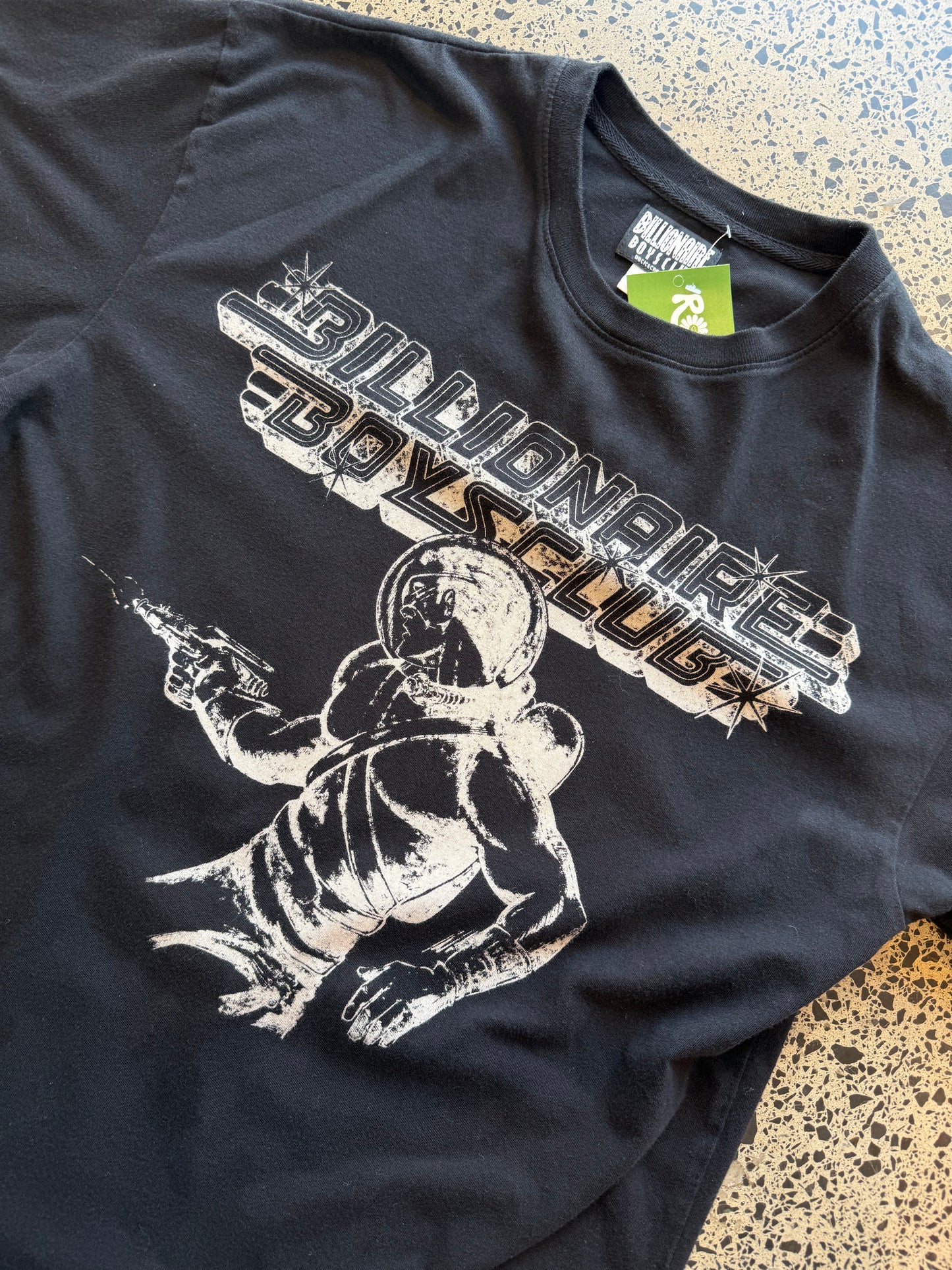 Billionaire Boys Club astronaut T-shirt in black, size M, laid on a polished concrete background — bold white astronaut graphic on soft cotton.