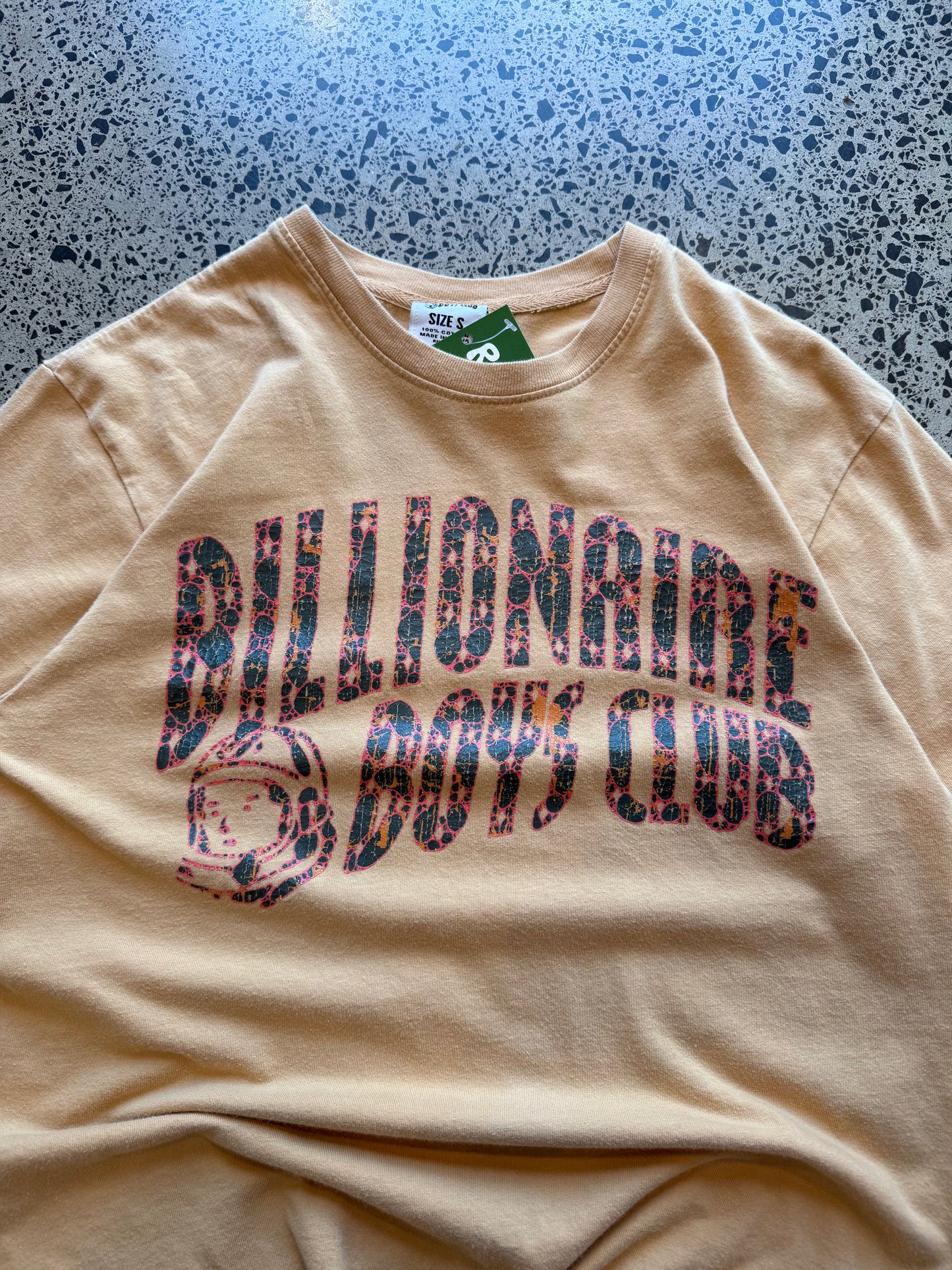 2022 Billionaire Boys Club tan logo T-shirt, size L, laid on polished concrete background — soft cotton with bold chest print.