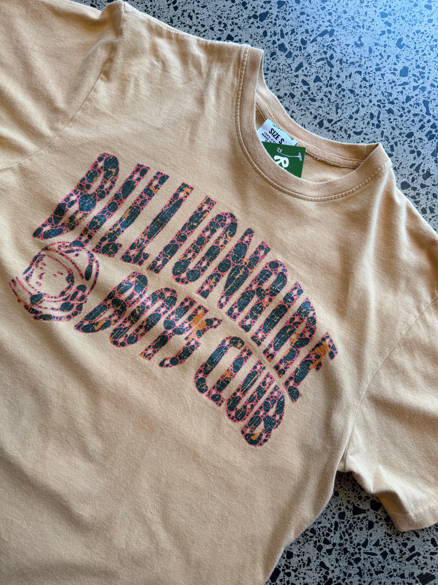 2022 Billionaire Boys Club tan logo T-shirt, size L, laid on polished concrete background — soft cotton with bold chest print.