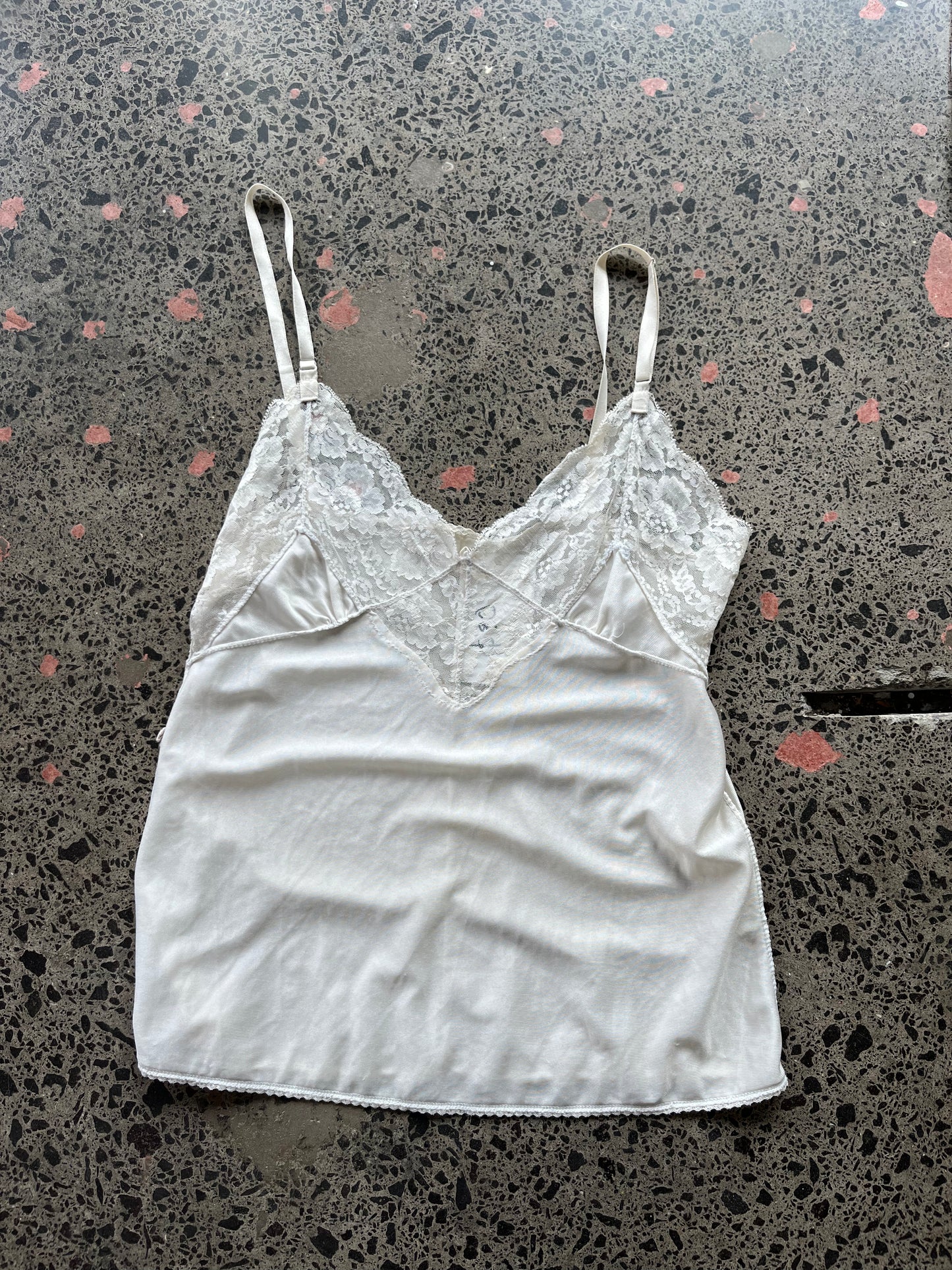 White lace camisole on a speckled gray surface
